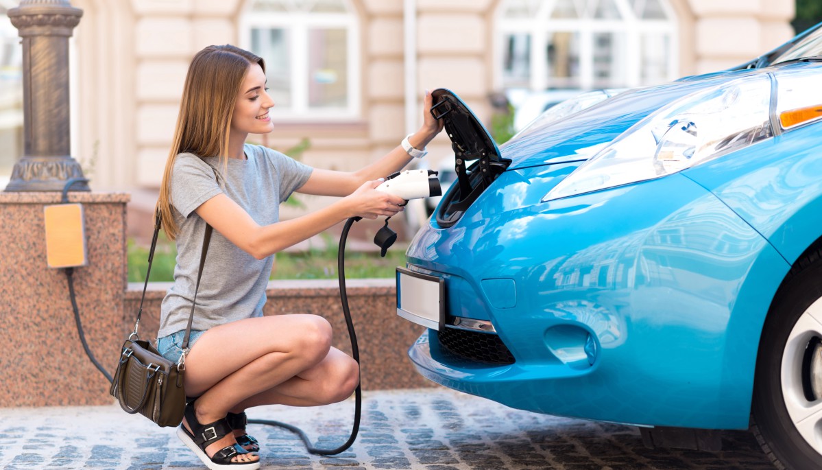 uśmiechnięta kobieta podpina swój samochód elektryczny do ładowarki Type 1