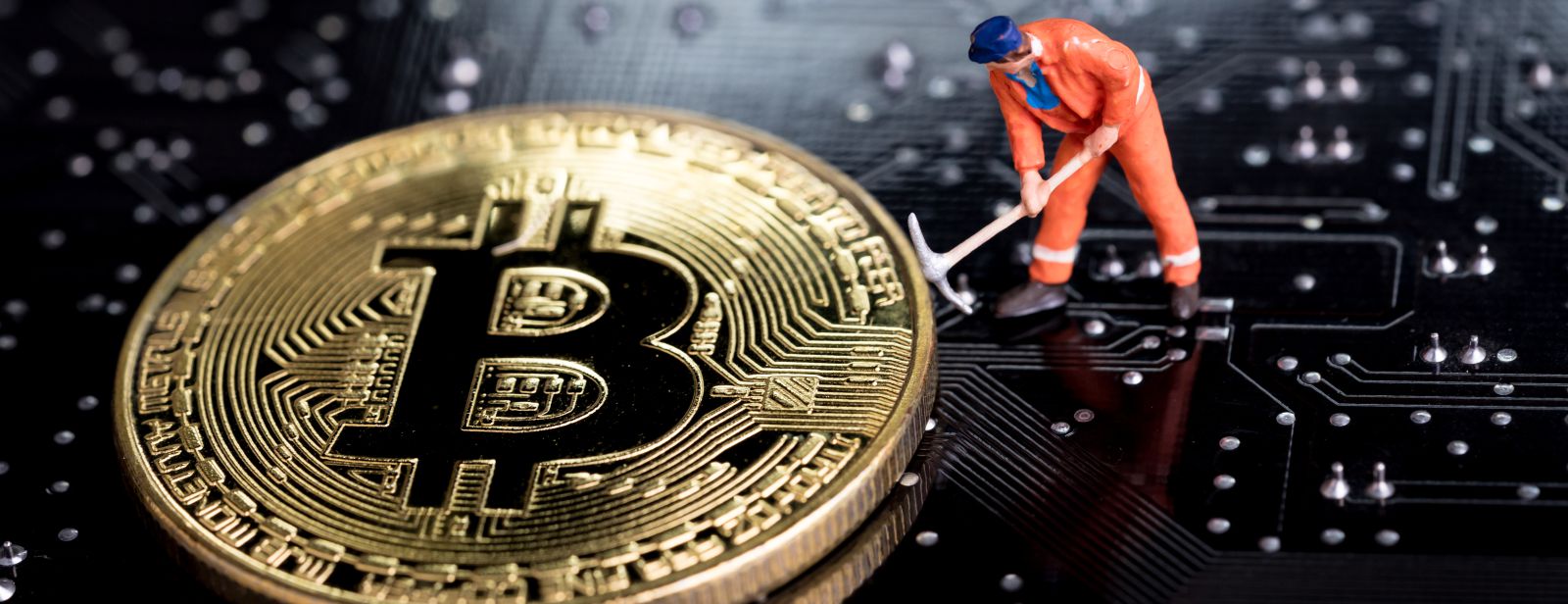 pomarańczowa figurka górnika na tle monety Bitcoin