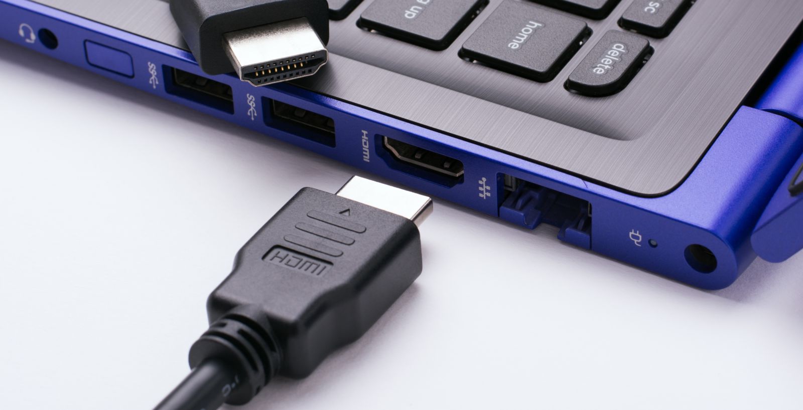 kabel HDMI leżący obok niebieskiego laptopa