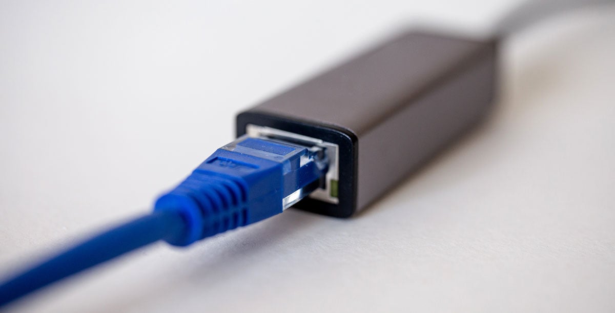 zbliżenie na końcówkę kabla Ethernetowego wpiętą do przejściówki sieciowej