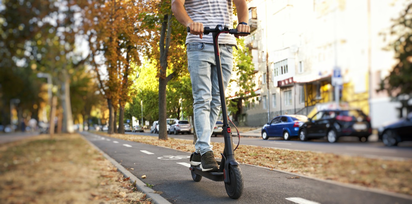  mężczyzna jedzie przez miasto po ścieżce rowerowej na elektrycznej hulajnodze
