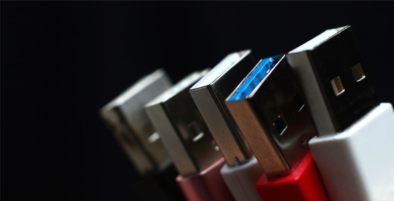 Wtyczki USB typu A różnych kolorów na czarnym tle